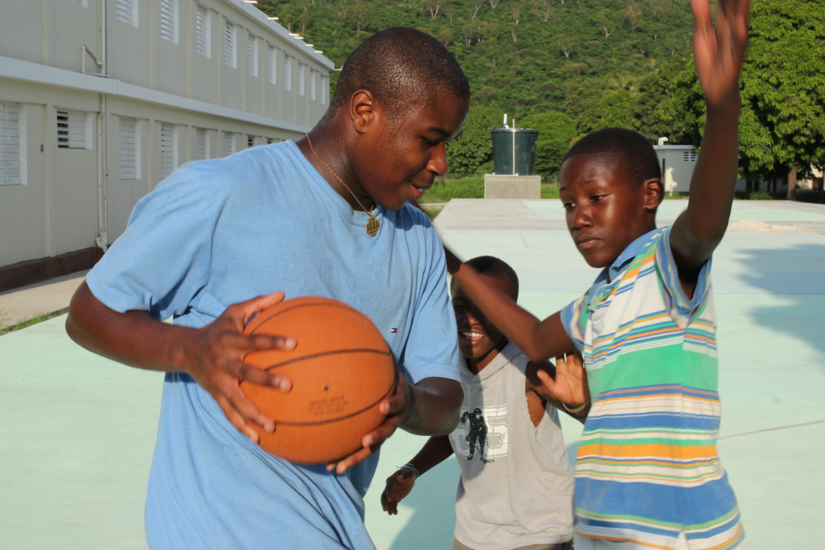 Anebi playing basketball with student in Haiti